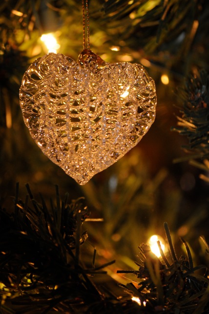 A closeup of a hand-blown glass heart ornament hanging on a tree.